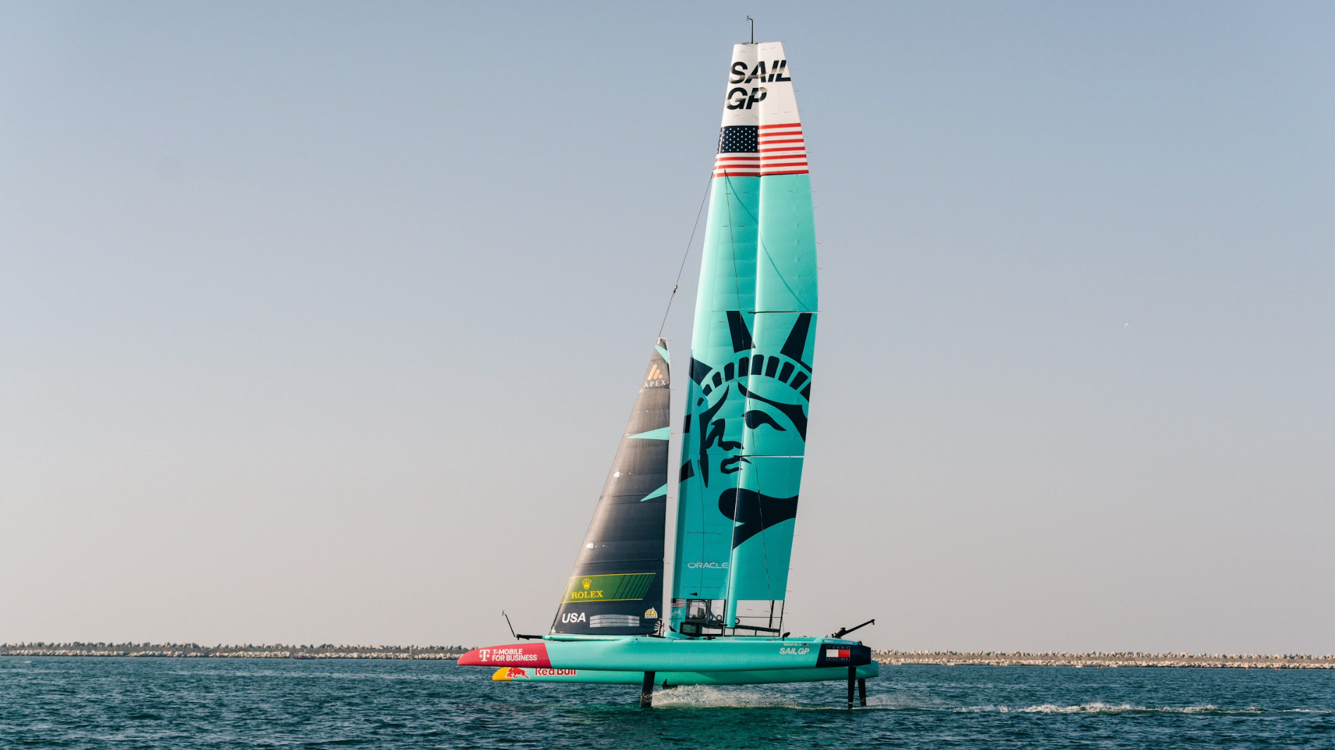 Foiling racing catamaran at speed on open ocean at dusk